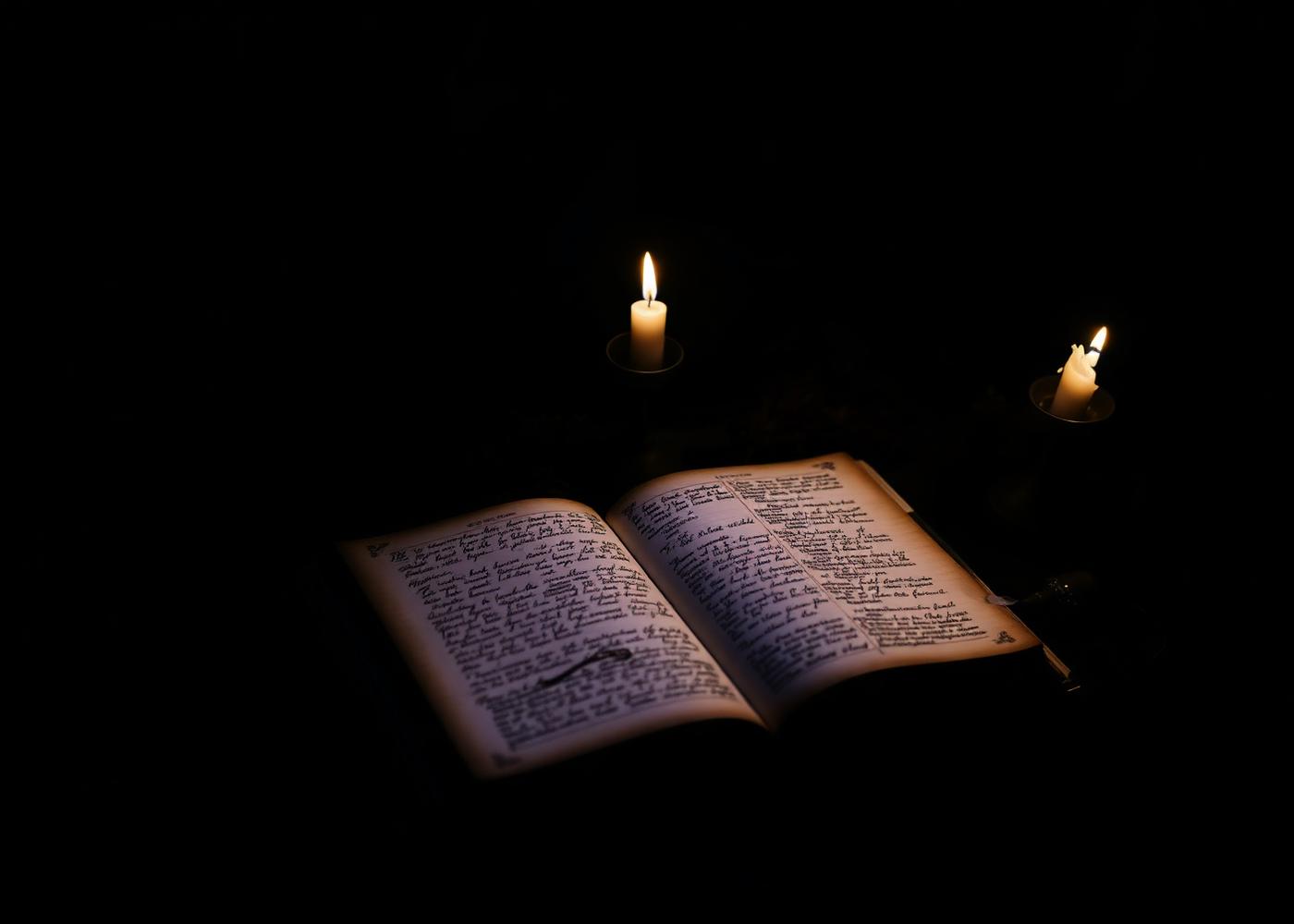 An open handwritten grimoire lit by candlelight, representing intuitive development mentorship